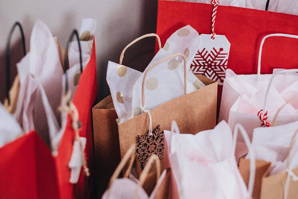 7 gift bags with tissue paper sit on the floor of a Woodhaven Commons home